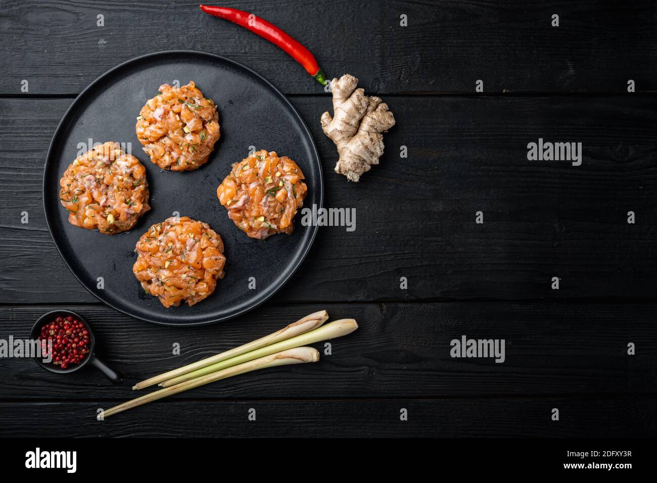 Raw fish patties with salmon fillet and lemongrass, on black wooden ...