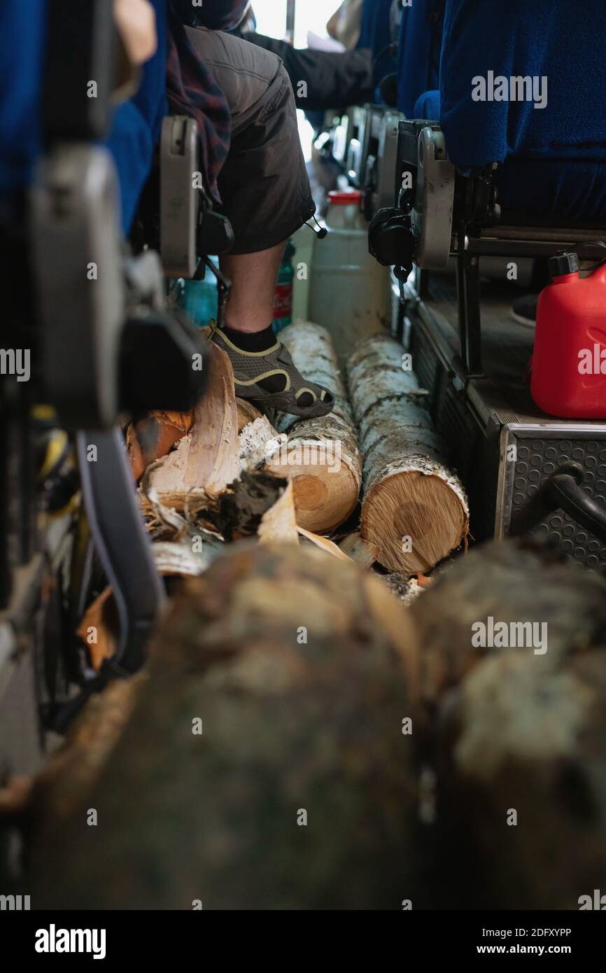 Firewood lying in cabin of tourist bus on floor. Transportation of logs. Extreme tourism Stock Photo