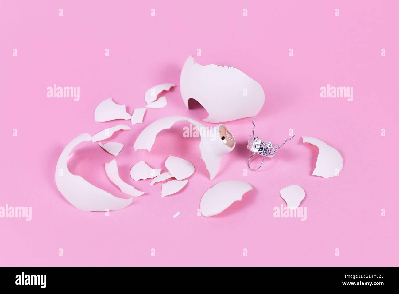 Broken white Christmas tree glass bauble shattered into many pieces on pink background Stock Photo