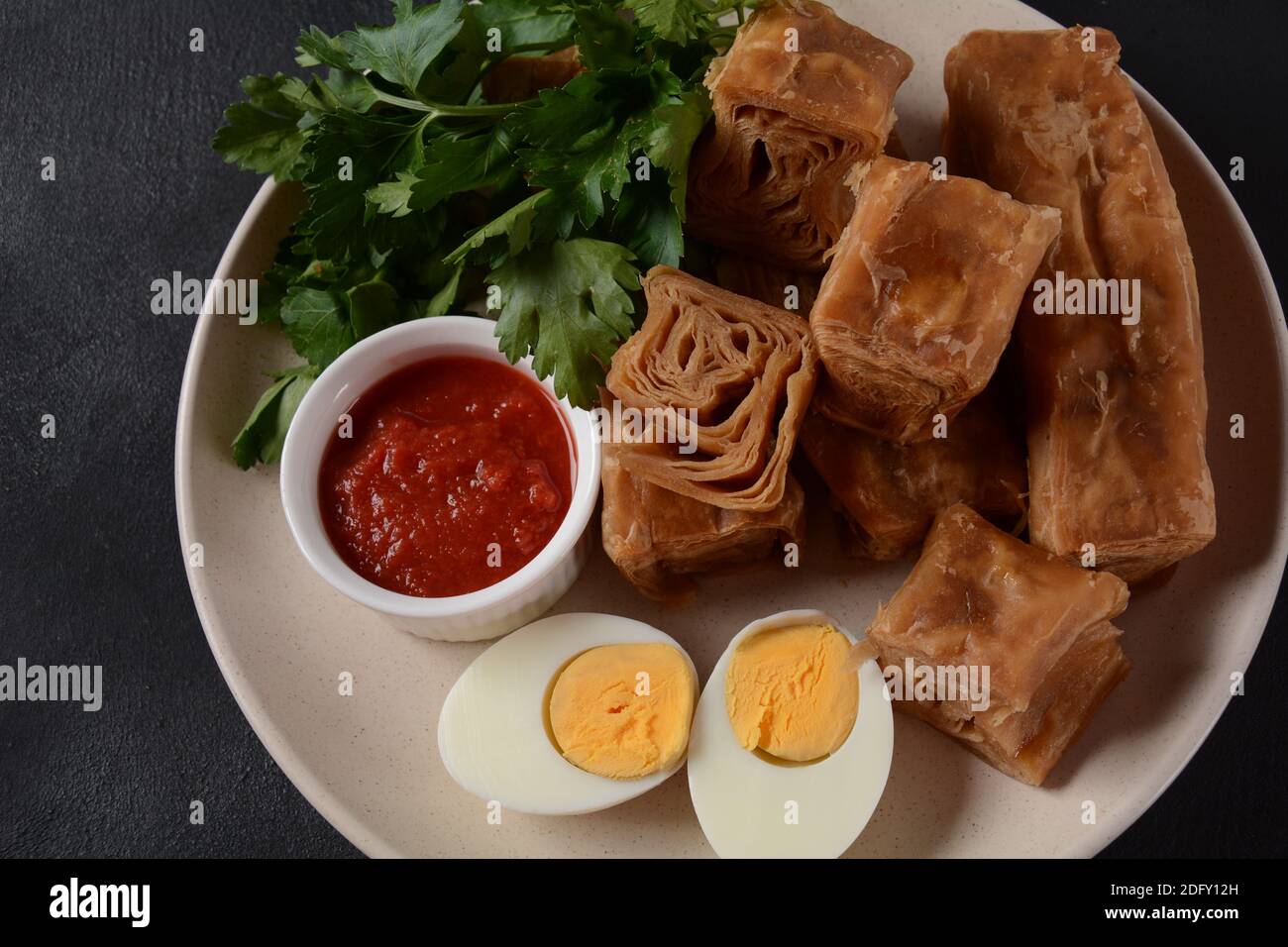 Jachnun or Jahnun, Yemenite Jewish pastry, served with fresh grated tomato and boiled egg and