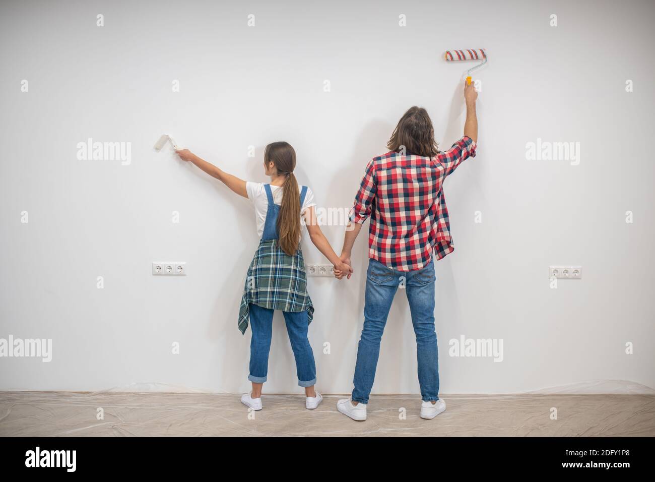 Young couple painting walls and holding hands Stock Photo - Alamy
