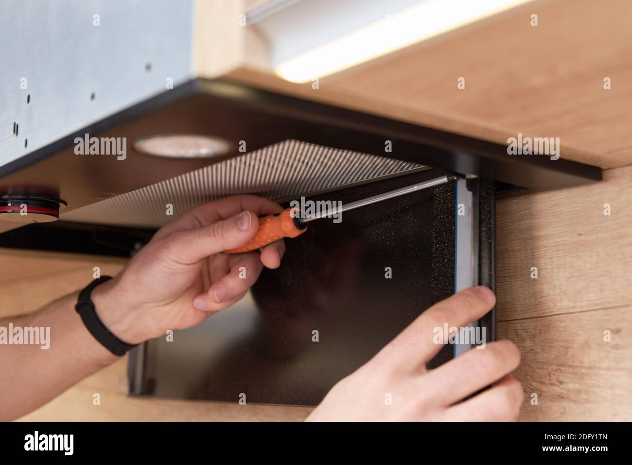 Man repairs hood in the kitchen. Replacement filter in cooker hood