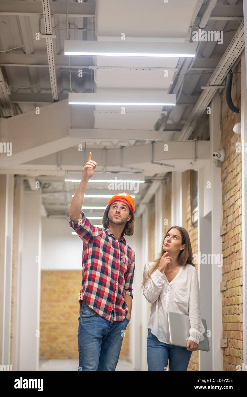 Construction worker in orange helmet talking to female customer Stock Photo