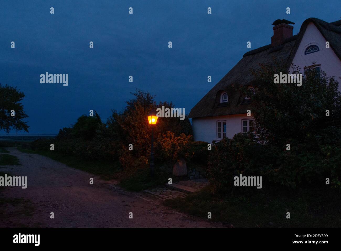 Amrum, Germany - October 12 Thatched house at a small path in the dusk Stock Photo