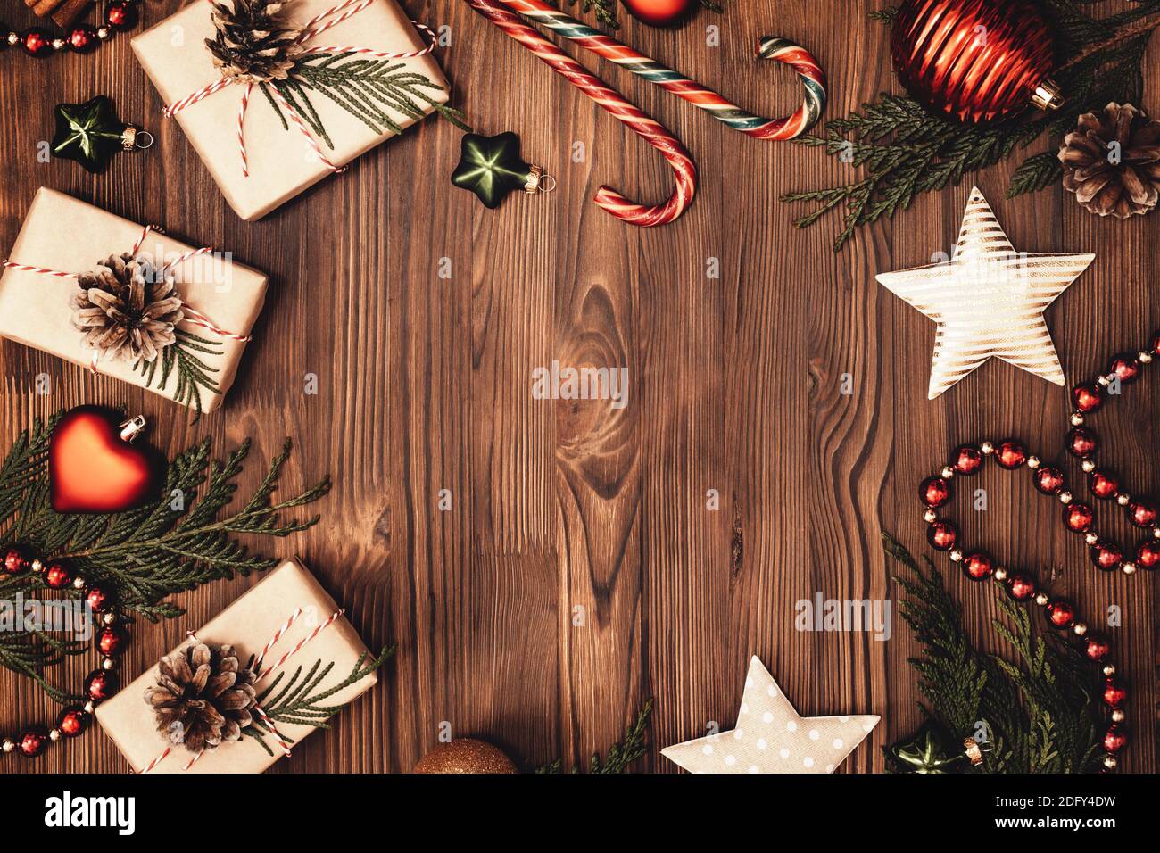 Christmas and New Year rustic traditional background with copy space. Festively decorated cedar branches on a dark brown old wooden board. Gift boxes, Stock Photo