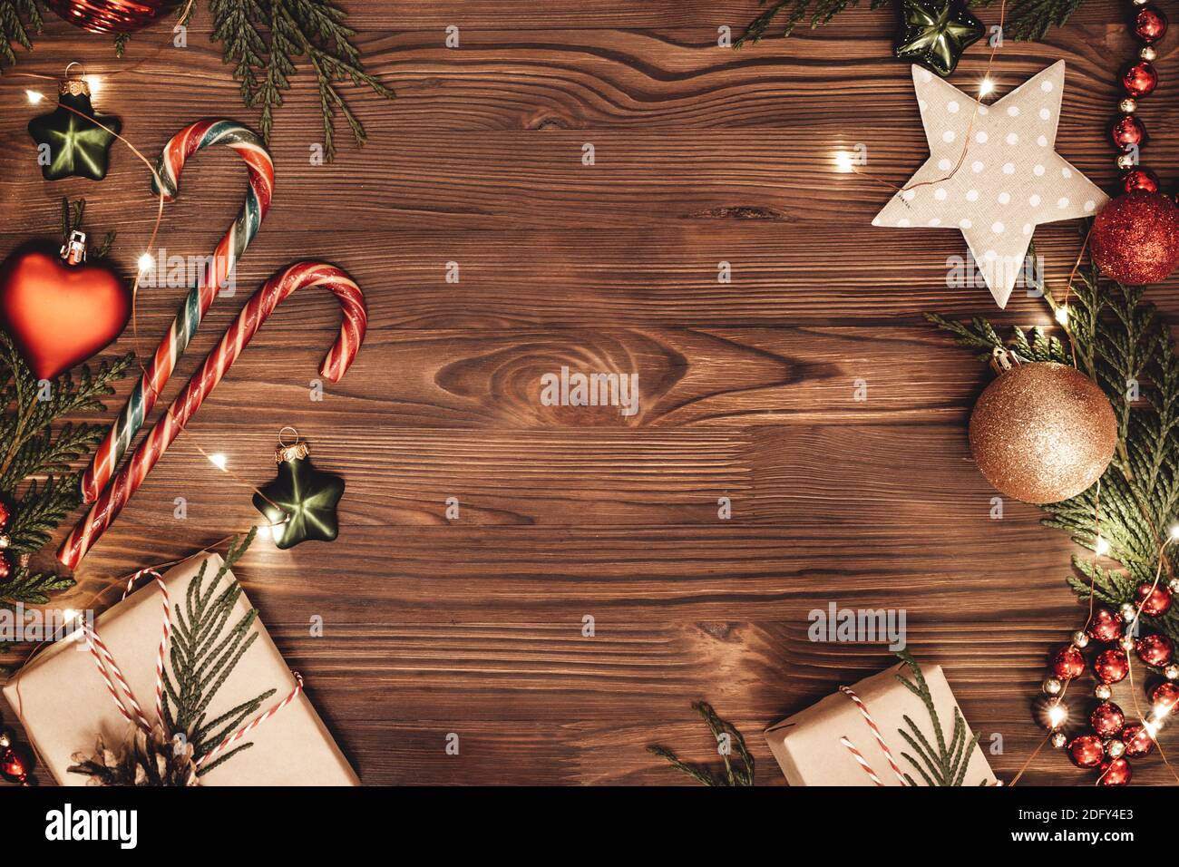 Christmas and New Year rustic traditional background with copy space. Festively decorated cedar branches on a dark brown old wooden board. Gift boxes, Stock Photo