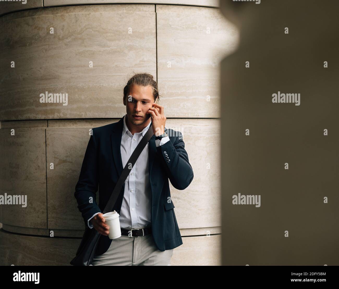 Young businessman with coffee in hand making call Stock Photo