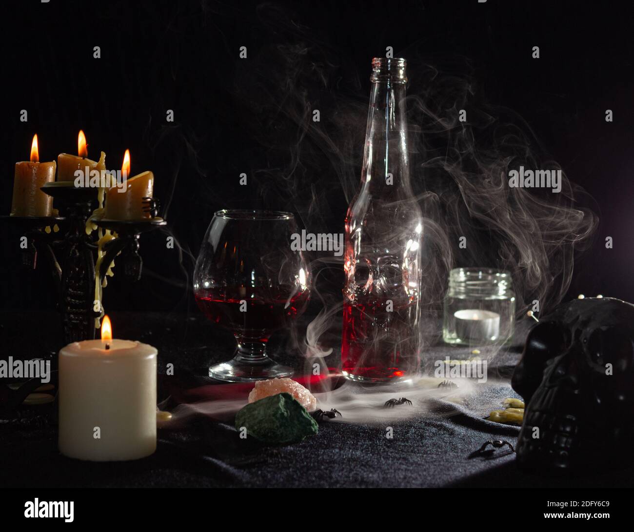 A bottle of red liquid like blood and a glass. Magical potion. The concept of wizards, witchcraft and magic. Halloween. Stock Photo