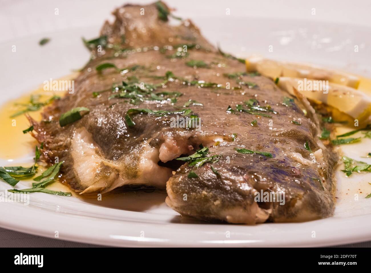 Whole Sole Meuniere, Breaded Fish on a White Plate with Brown Butter, Parsley and Lemon Stock Photo