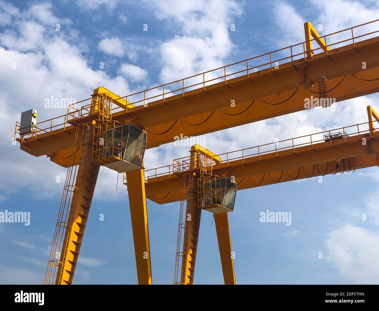 Gantry cranes opposite cloudy sky. Industrial lifting machinery. Hoist