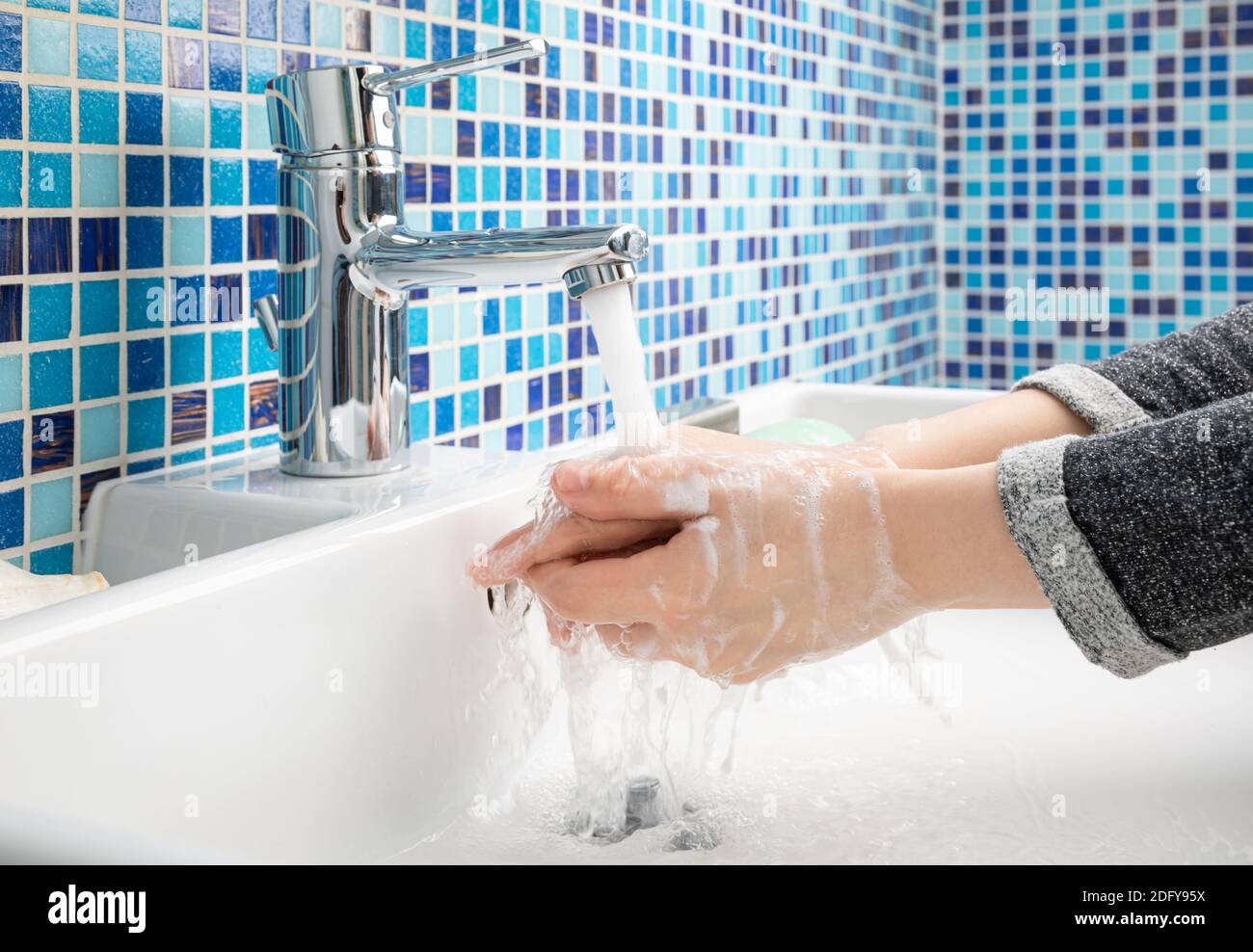 Child washing hands with antibacterial soap and water performing basic protective measures against spreading of coronavirus COVID-19 disease Stock Photo