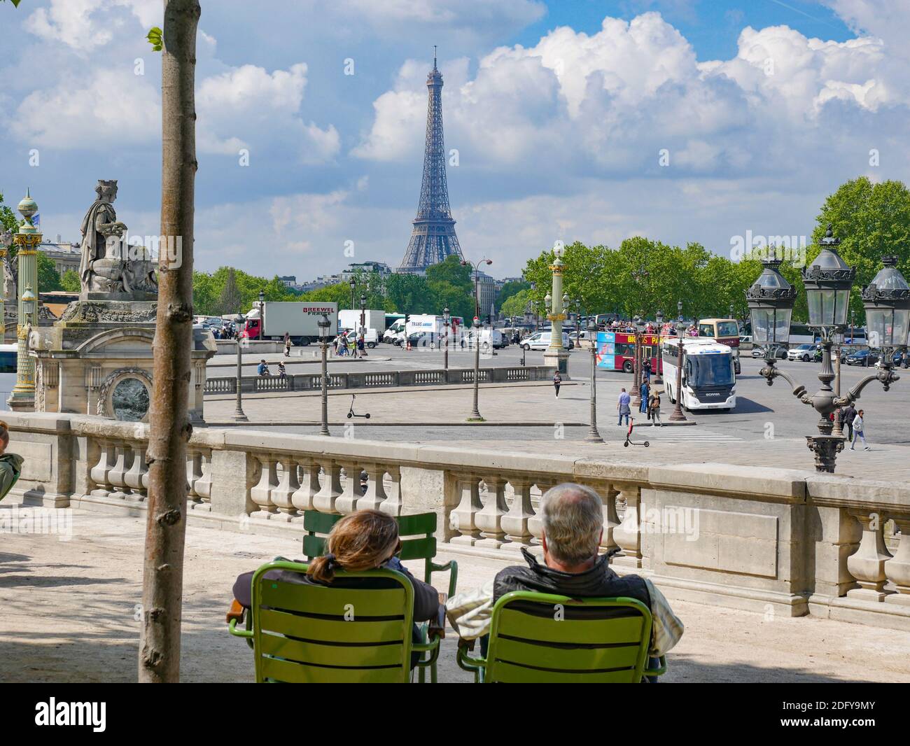 Couple sit looking at Eiffel Tower over Place de la Concorde in Paris ...