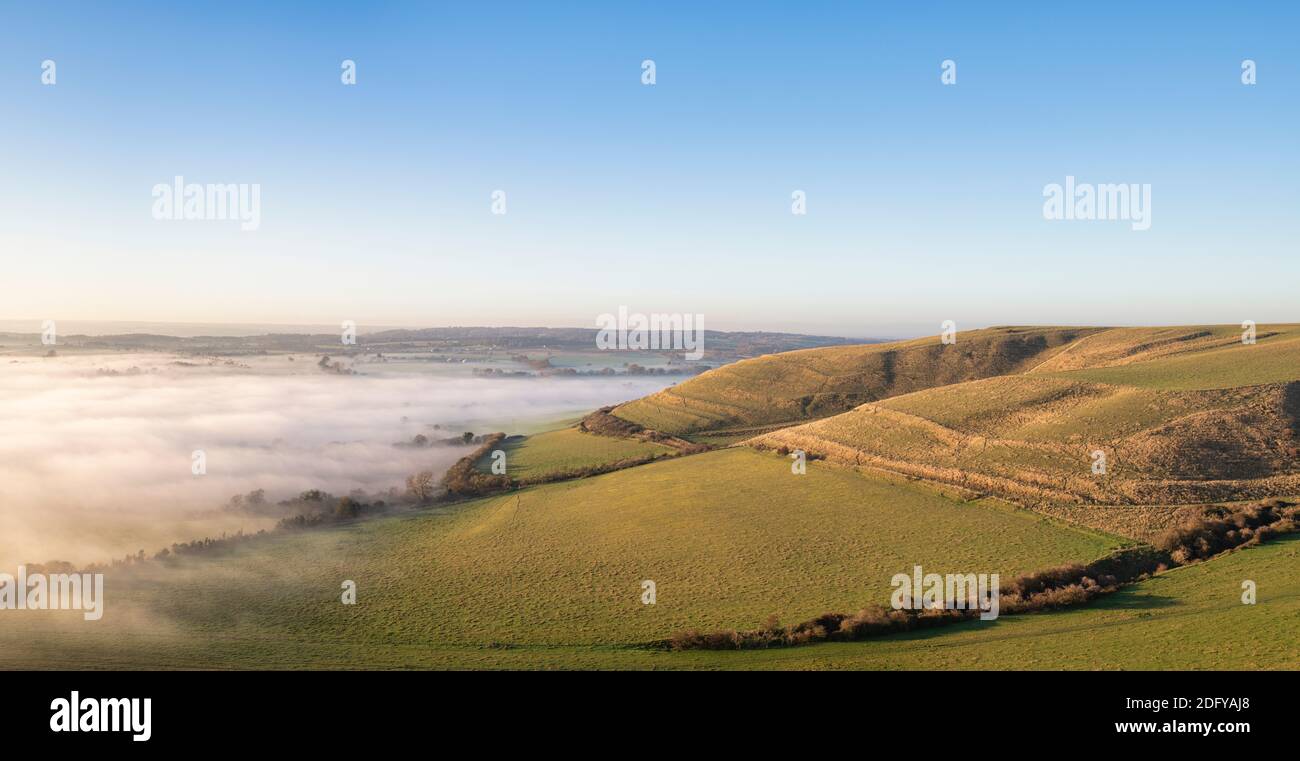 Late Afternoon Fog over the wiltshire countryside from Roundway Hill in the Wessex Downs. Vale of Pewsey, Wiltshire, England. Panoramic Stock Photo