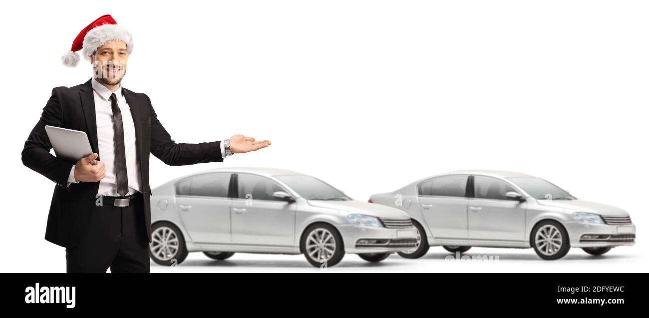Salesman with a santa claus hat showing a car in a showroom isolated on white background Stock Photo
