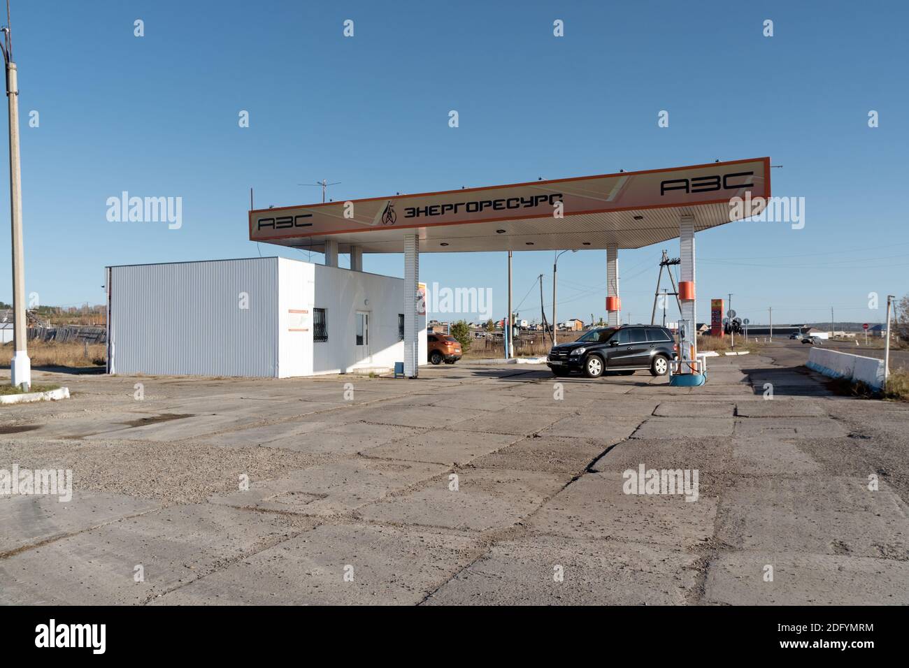 A car stands near a small roadside gas station with the name - Power resource, on a sunny autumn day. Stock Photo