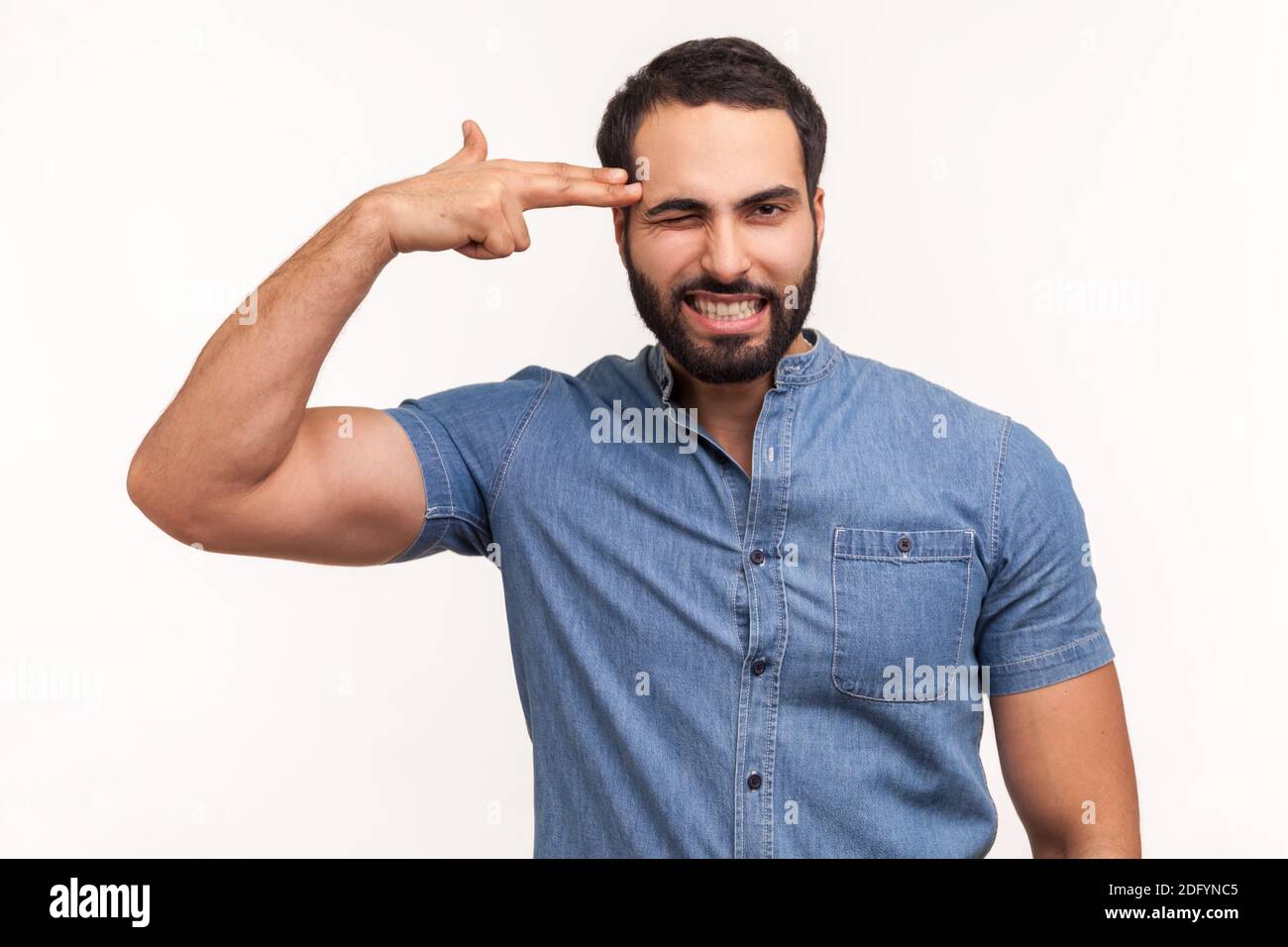 Depressed lonely man with beard holding fingers near temple pretending holding gun, going to make shot, faced with problems and crisis. Indoor studio Stock Photo