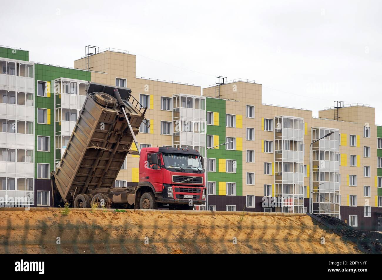 A dump truck dumps a site in front of a newly built apartment building in the village of Tayozhny, Krasnoyarsk Territory. Russia. Stock Photo