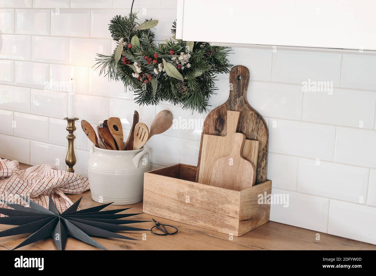 Closeup of kitchen interior. Christmas decoration. Advent floral hoop wreath. Black paper star. White brick wall, metro tiles, wooden countertops with Stock Photo