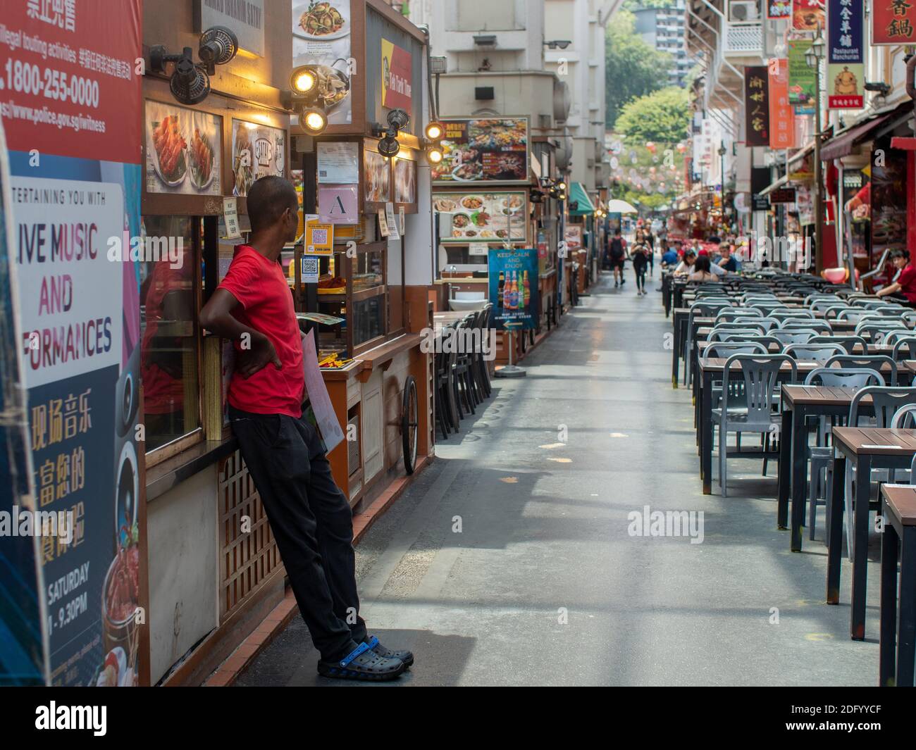 A man looks on empty tables in a hawker food court in central Singapore, SE Asia. Stock Photo