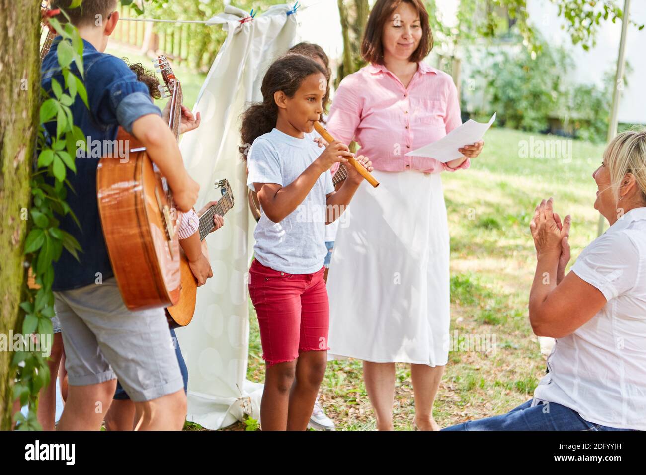 Girl plays the flute in a children's band at the talent show performance at the summer camp Stock Photo