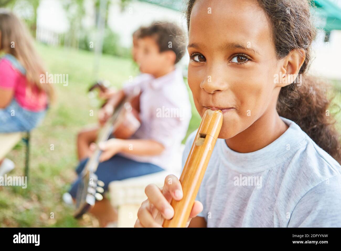 Girl learns to play the flute with friends in music class in summer camp course Stock Photo