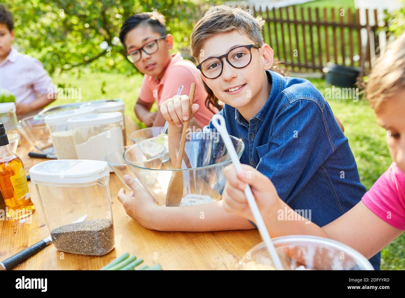 Children preparing a salad in the cooking class for healthy eating at summer camp Stock Photo