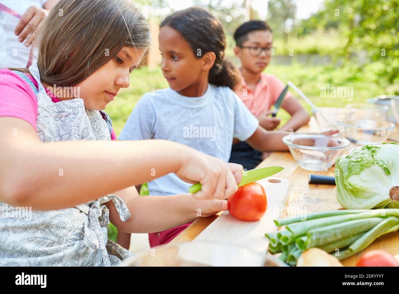 Children at summer camp cooking class prepare salad and learn about healthy eating Stock Photo