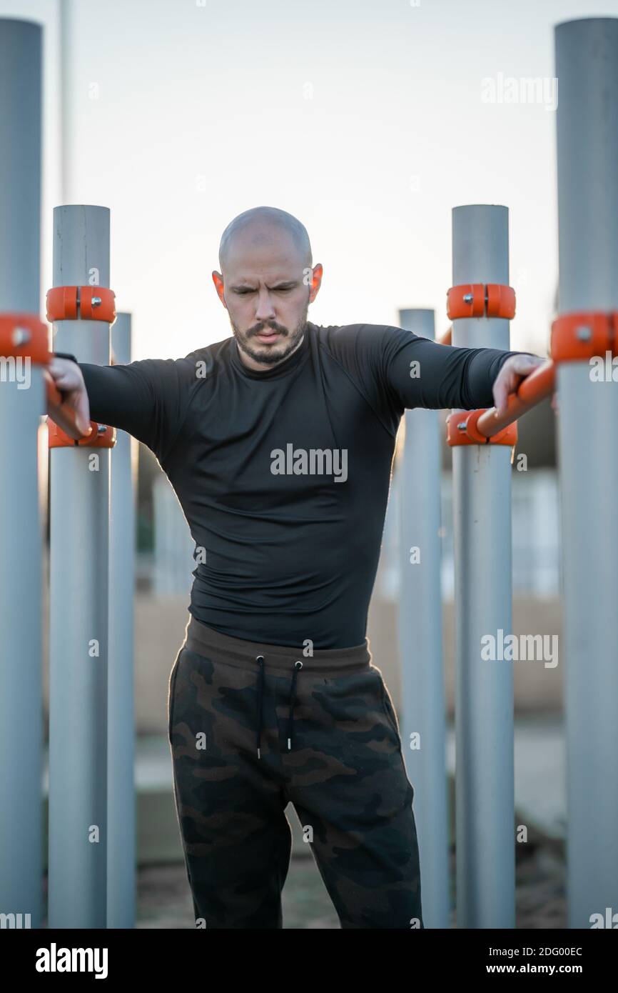 A young Hispanic man having a rest after exercising on the horizontal bars Stock Photo