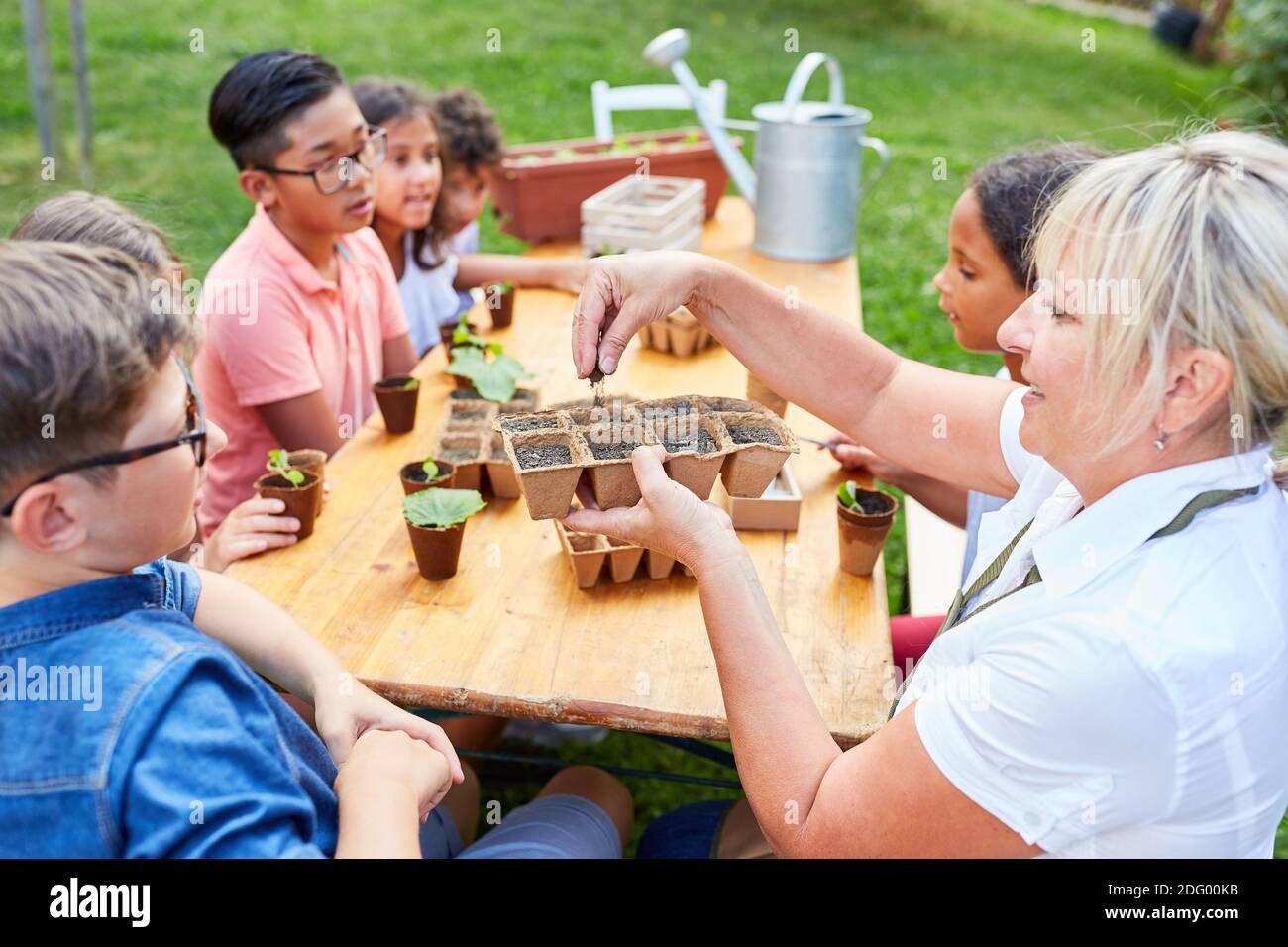 Teacher shows children how to sow plants in the nature conservation project of the summer school Stock Photo