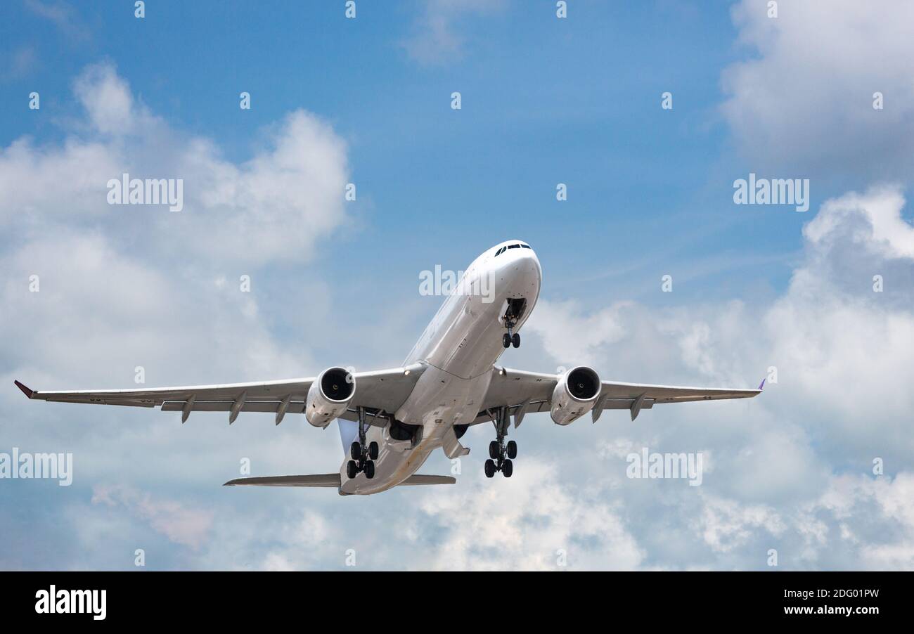 Passenger airplane taking off in bright cloudy sky. Wide-body commercial airliner over blue sky. Vacation, aviation, travel concept Stock Photo