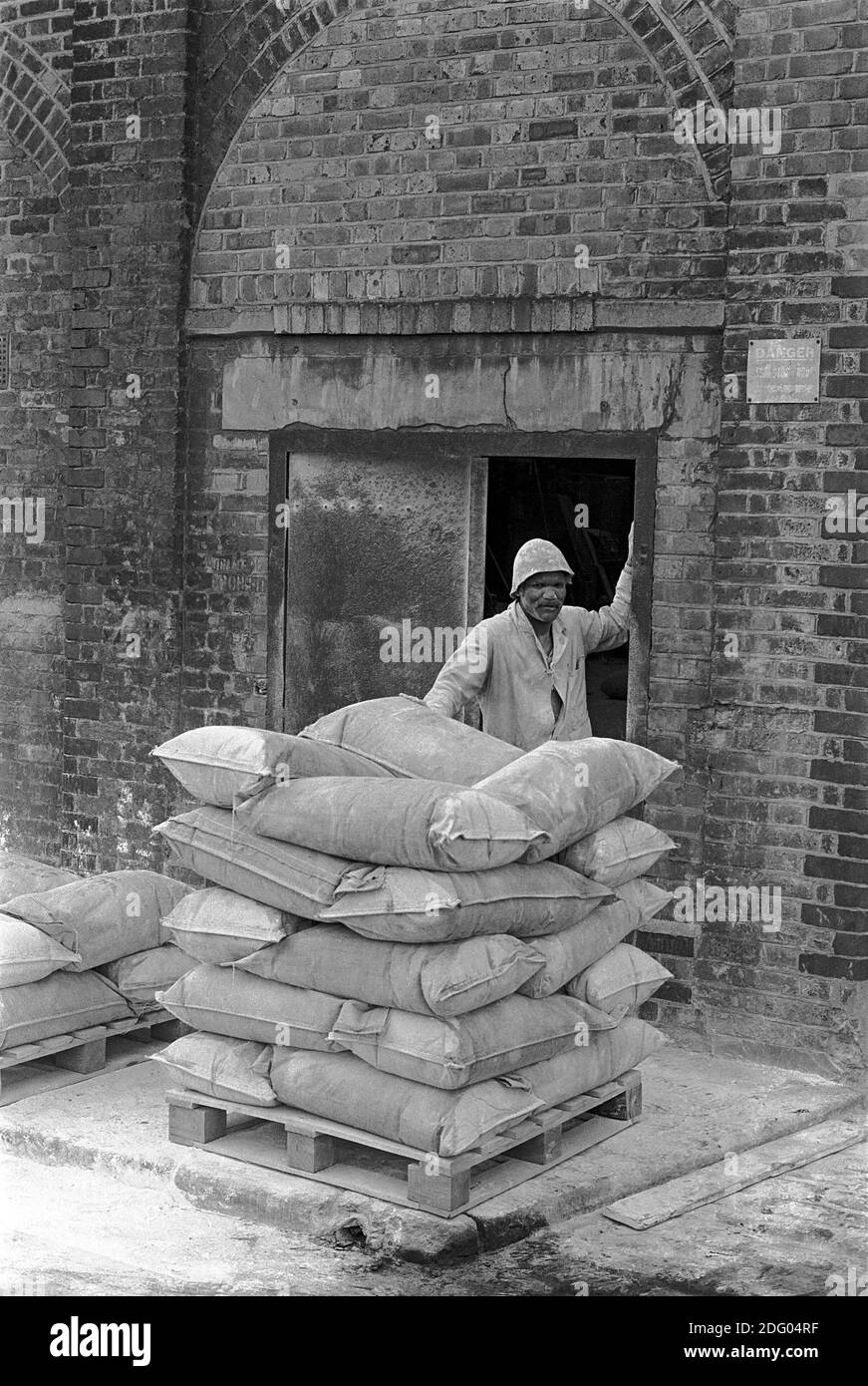UK, London, Docklands, Isle of Dogs. early 1974. Factory near to Coldharbour. Partex Parting Powder manufacture, Foundrimet, Foundry & Metallurgical. The bags of powder are stacked, by this worker, ready for delivery. Exported to Sweden. the workers were given 3 pints of milk a day because of the dust, £10 Xmas bonus and drinks in The Gun, a nearby pub. Stock Photo