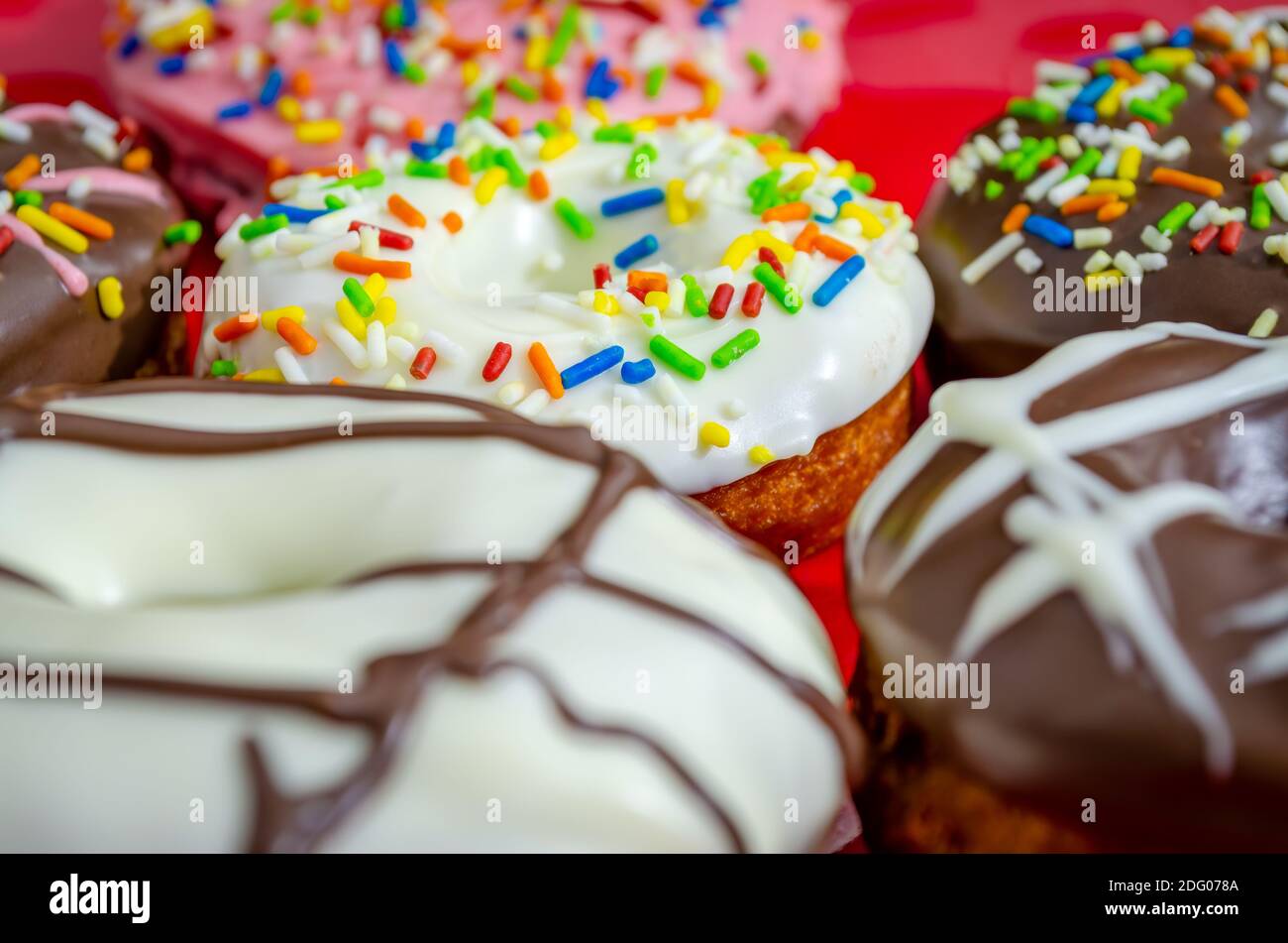 Closeup of various flavored donuts with colorful sugar strands sprinkled on them Stock Photo