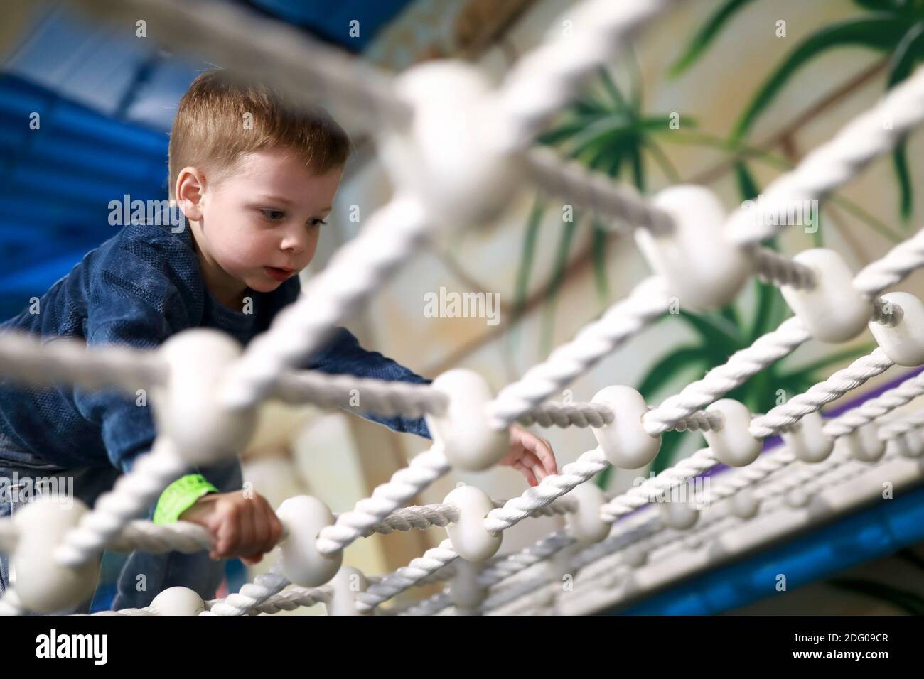 Child crawling on rope mesh at playground Stock Photo Alamy