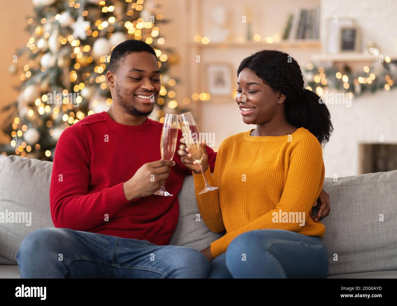 Millennial cheerful african american guy and woman clink glasses of champagne Stock Photo
