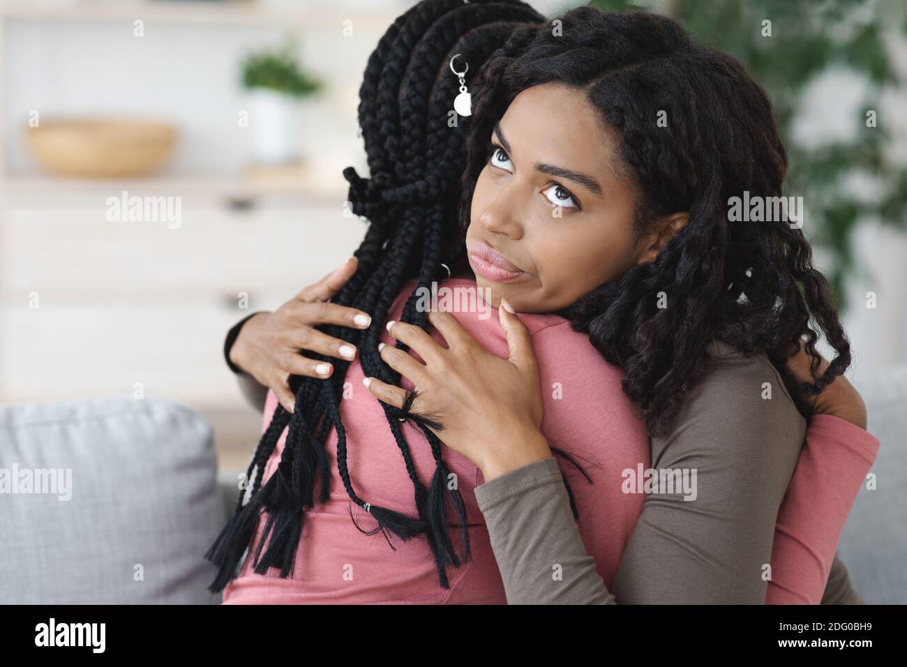 Irritated black lady hugging her girlfriend, fake friendship Stock Photo