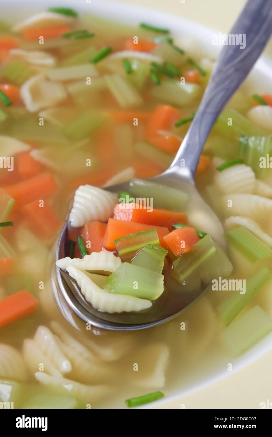 Aufnahme mit geringer TiefenschÃ¤rfe einer GemÃ¼sesuppe mit Nudeln in einem gelben Teller. Stock Photo