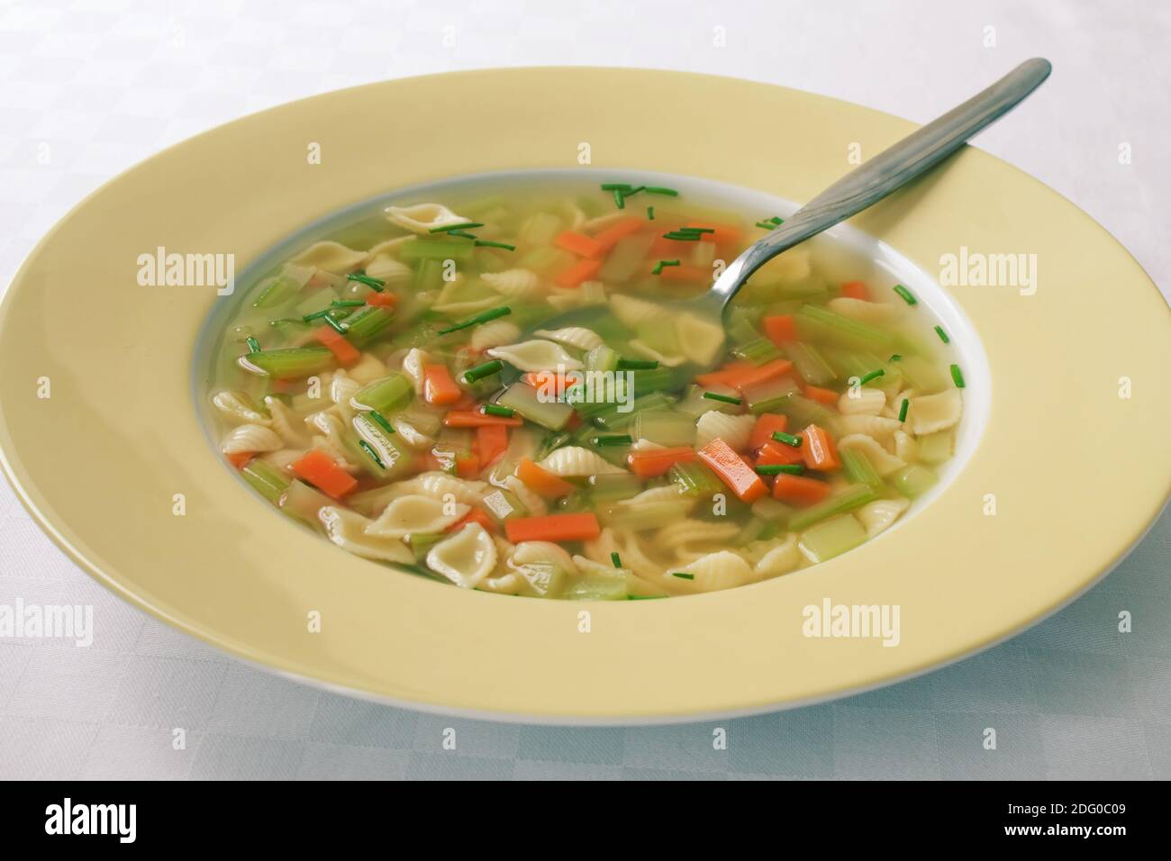 Aufnahme mit geringer TiefenschÃ¤rfe einer GemÃ¼sesuppe mit Nudeln in einem gelben Teller. Stock Photo