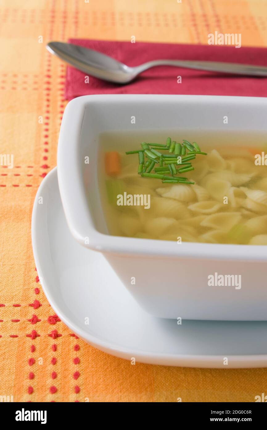 Aufnahme mit geringer TiefenschÃ¤rfe einer GemÃ¼sesuppe mit Nudeln auf einer orangen Tischdecke. Stock Photo