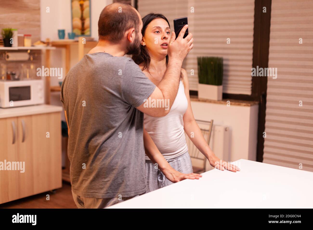 Husband having disagreement with cheating wife showing text from another man in her phone. Frustrated offended irritated accusing woman of infidelity arguing her with messages. Stock Photo