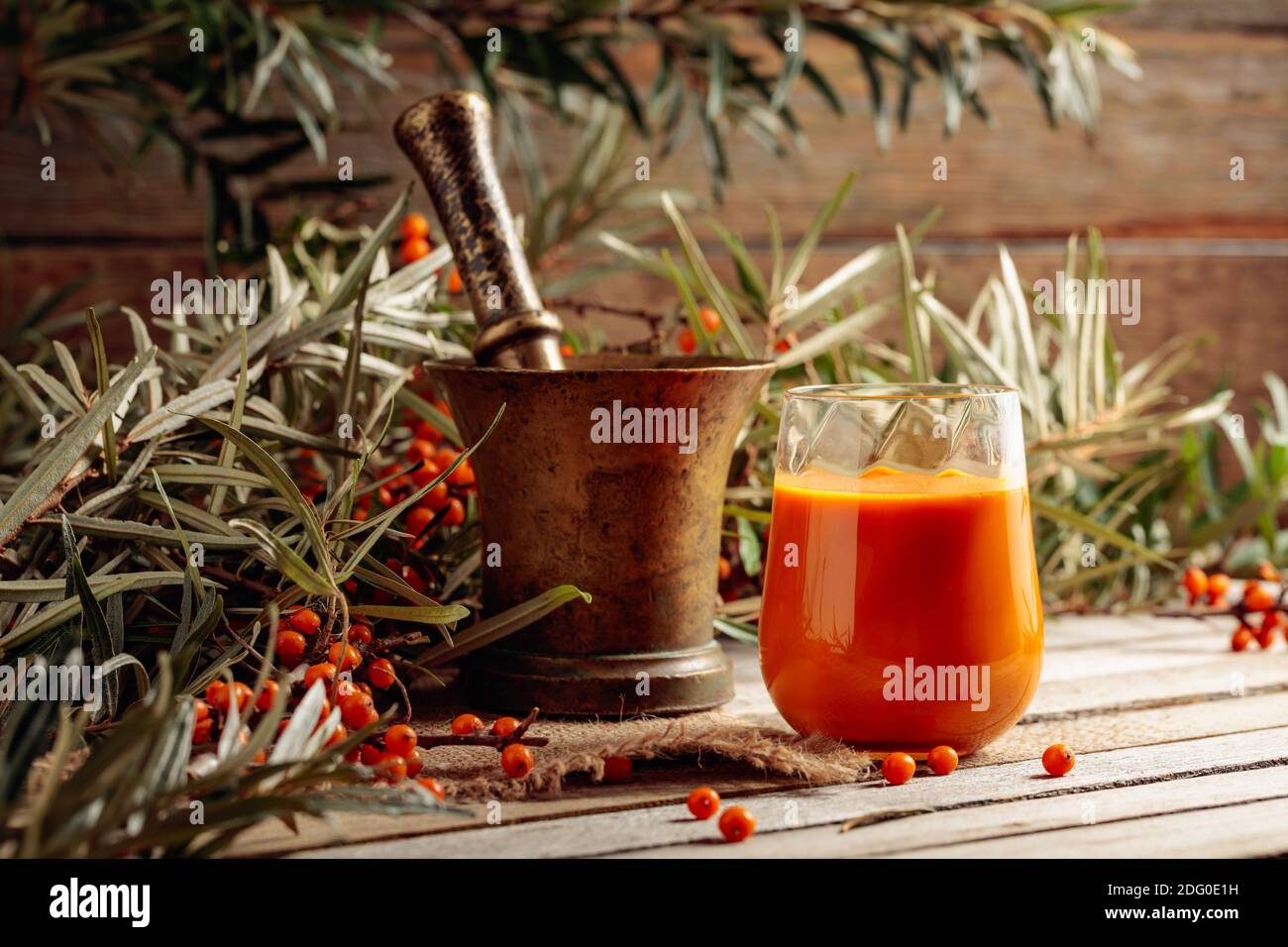 A glass of sea buckthorn juice with fresh berries on an old wooden ...