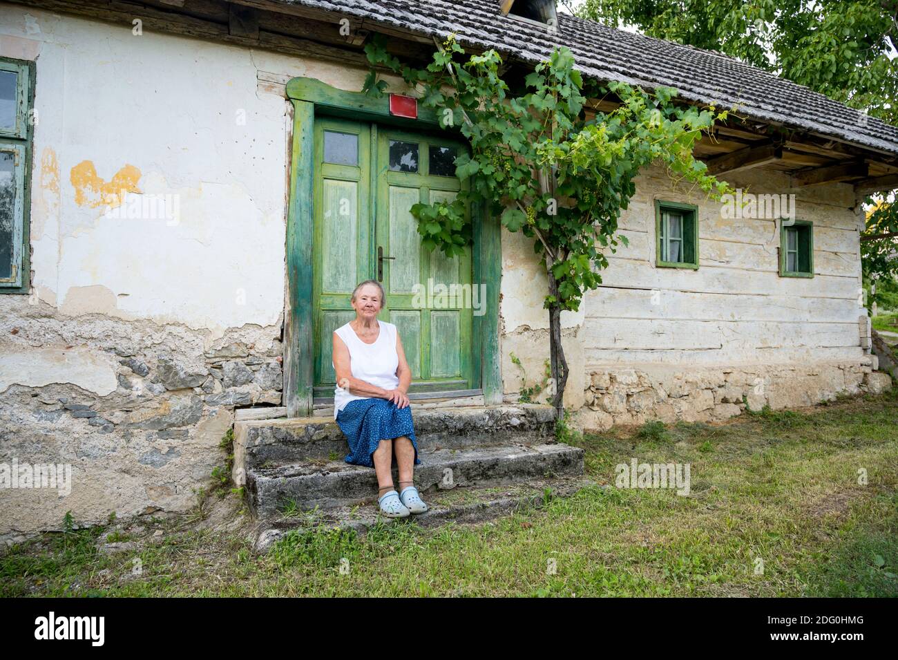 Elder woman sitting at the steps of old house and remembering Stock ...