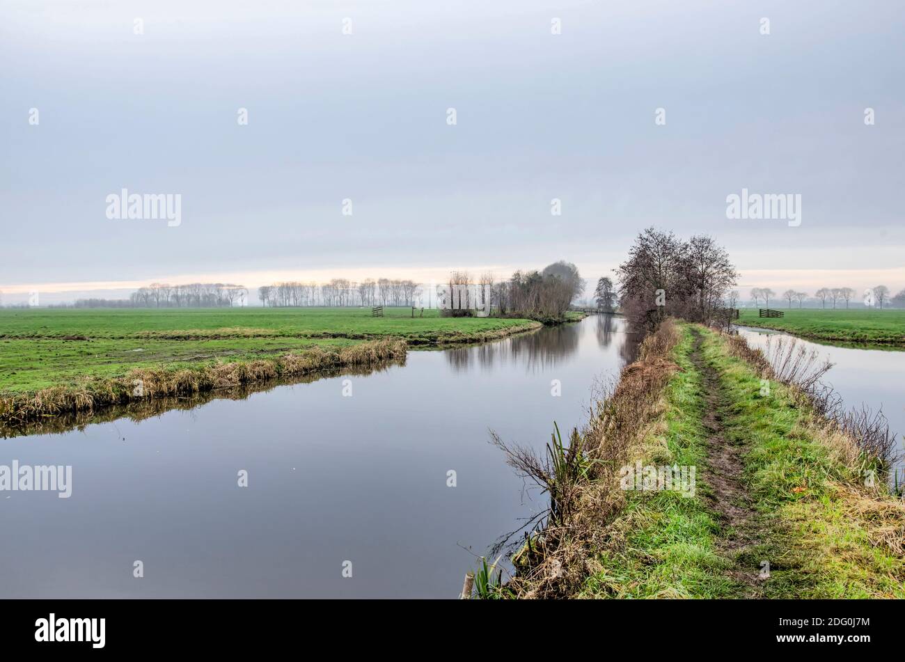 Narrow and muddy hiking trail known as the Tiendweg between Haastrecht and Oudewater in the Netherlands on a cold but windless day in December Stock Photo