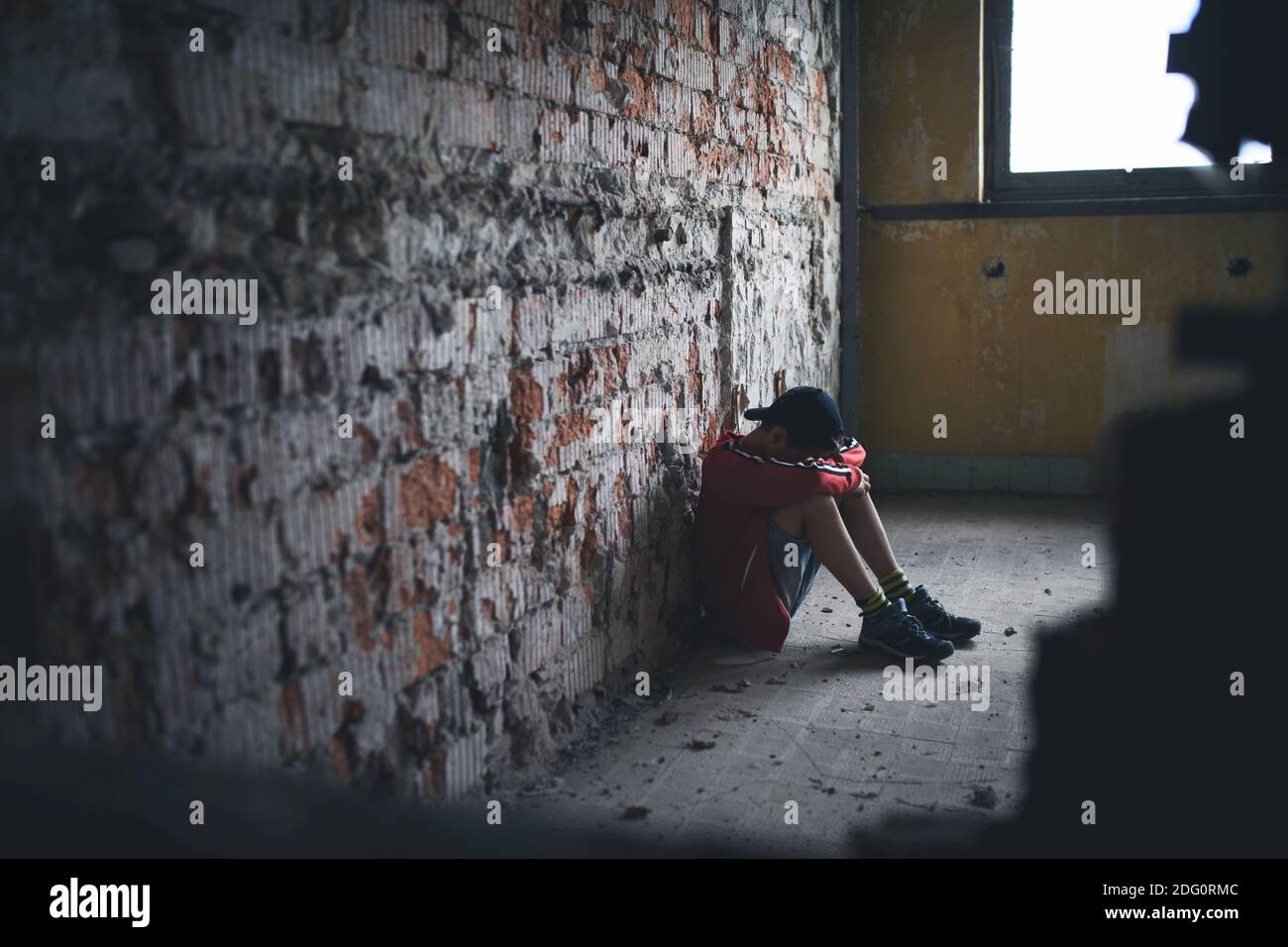 Sad and disappointed teenagers boy sitting indoors in abandoned building. Stock Photo