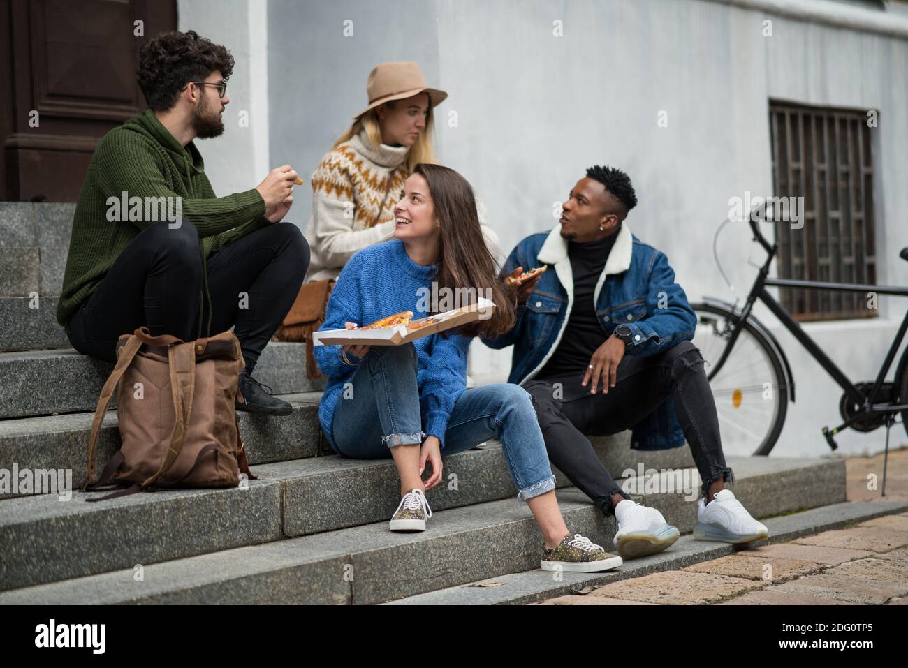 Group of young people outdoors in town, eating pizza. Coronavirus concept. Stock Photo