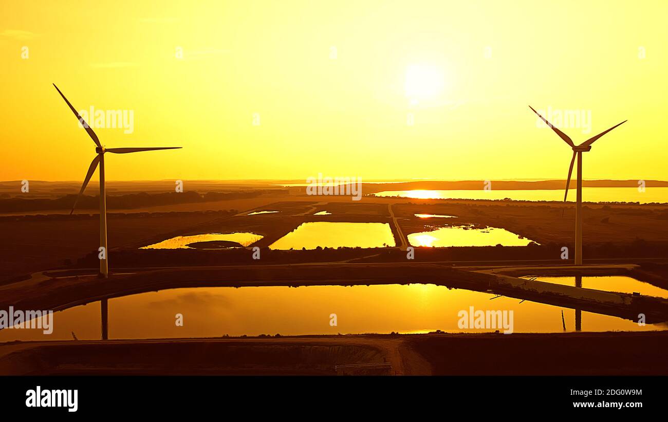 Large wind turbines generating clean renewable energy in a hot orange ...