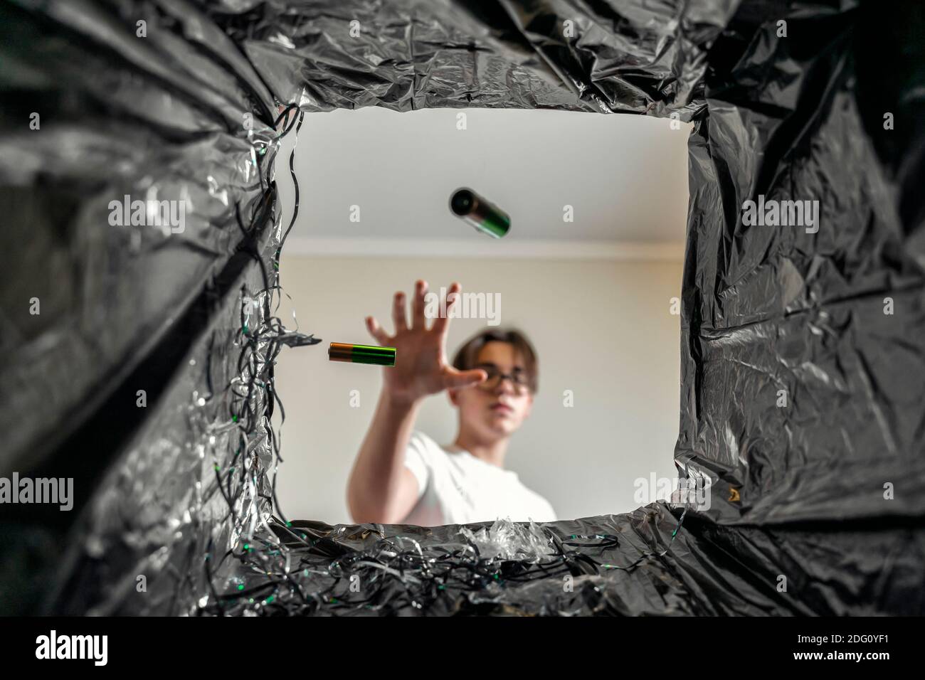 man throws batteries in the trash. battery recycling. view from the