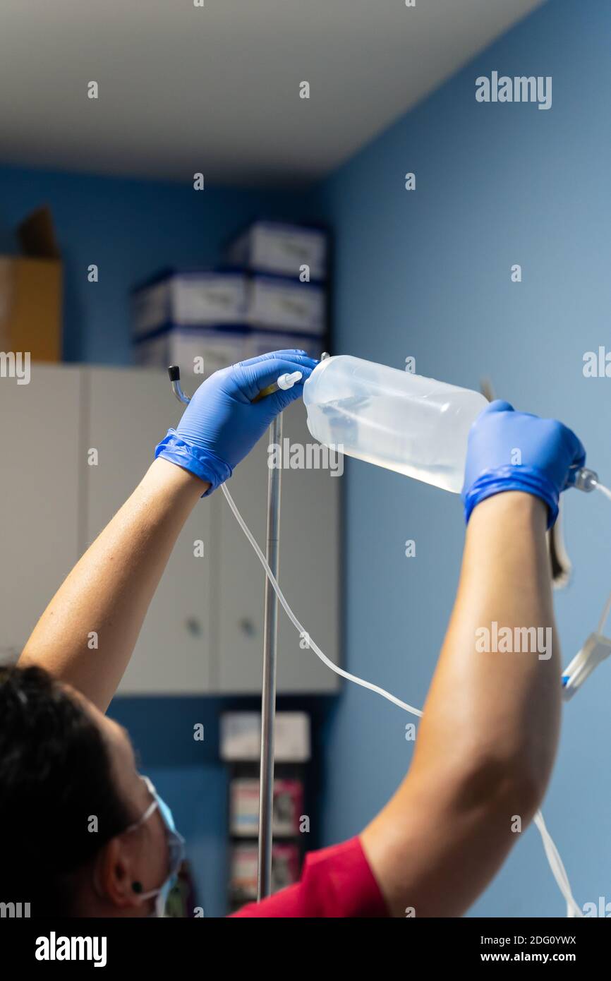 Nurse placing physiological saline solution in a serum hanger Stock
