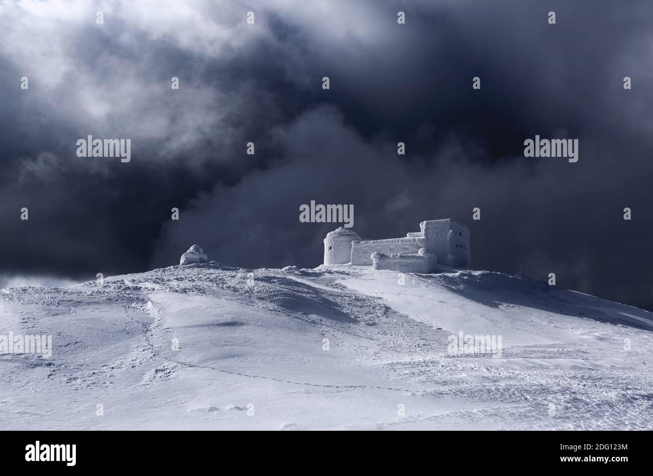The old observatory covered with textured snow. Dramatic stormy sky with gray clouds. Winter scenery. Beautiful landscape of high mountains. Wallpaper Stock Photo