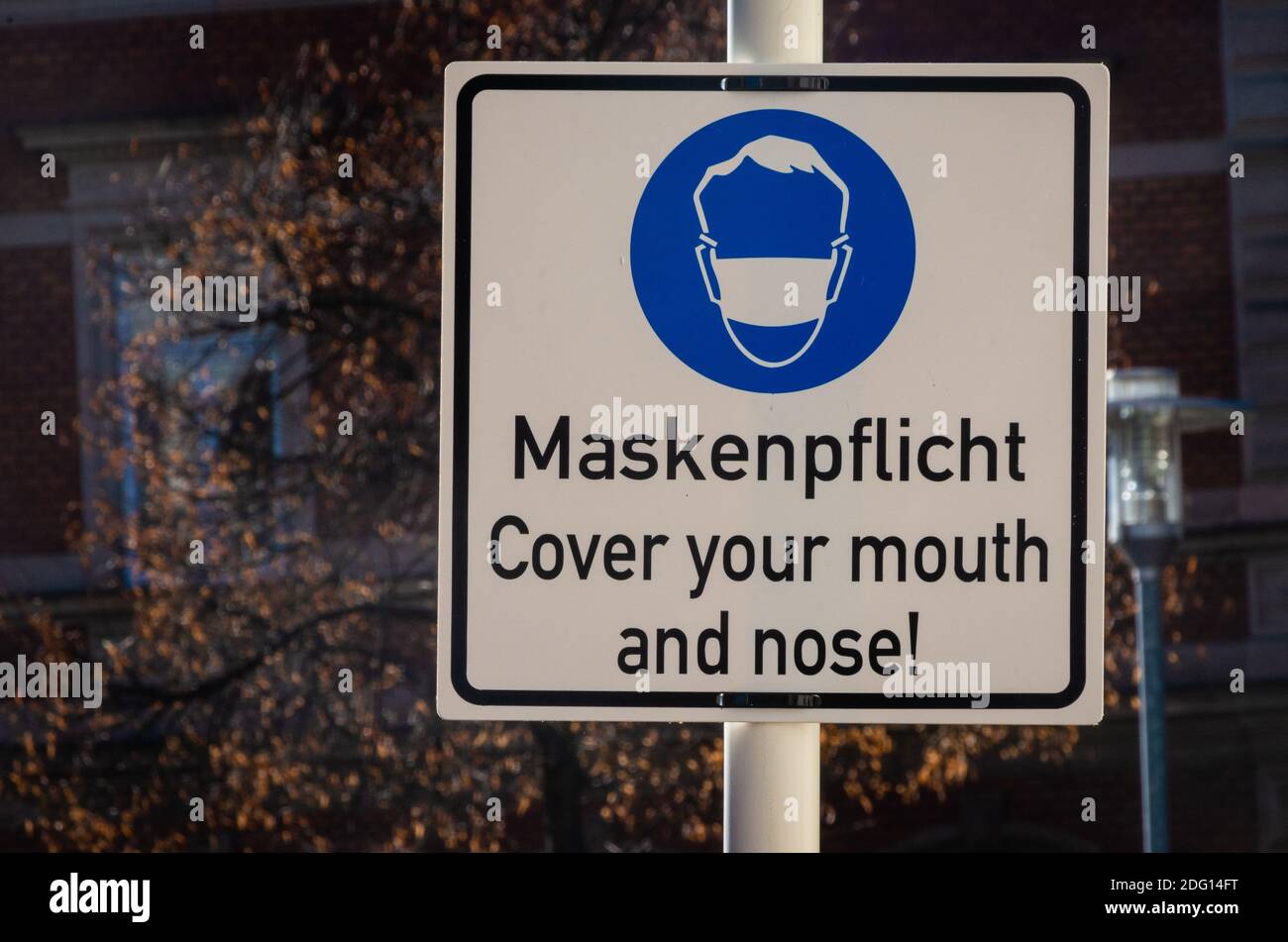 signpost wear a mask in german and english language Stock Photo