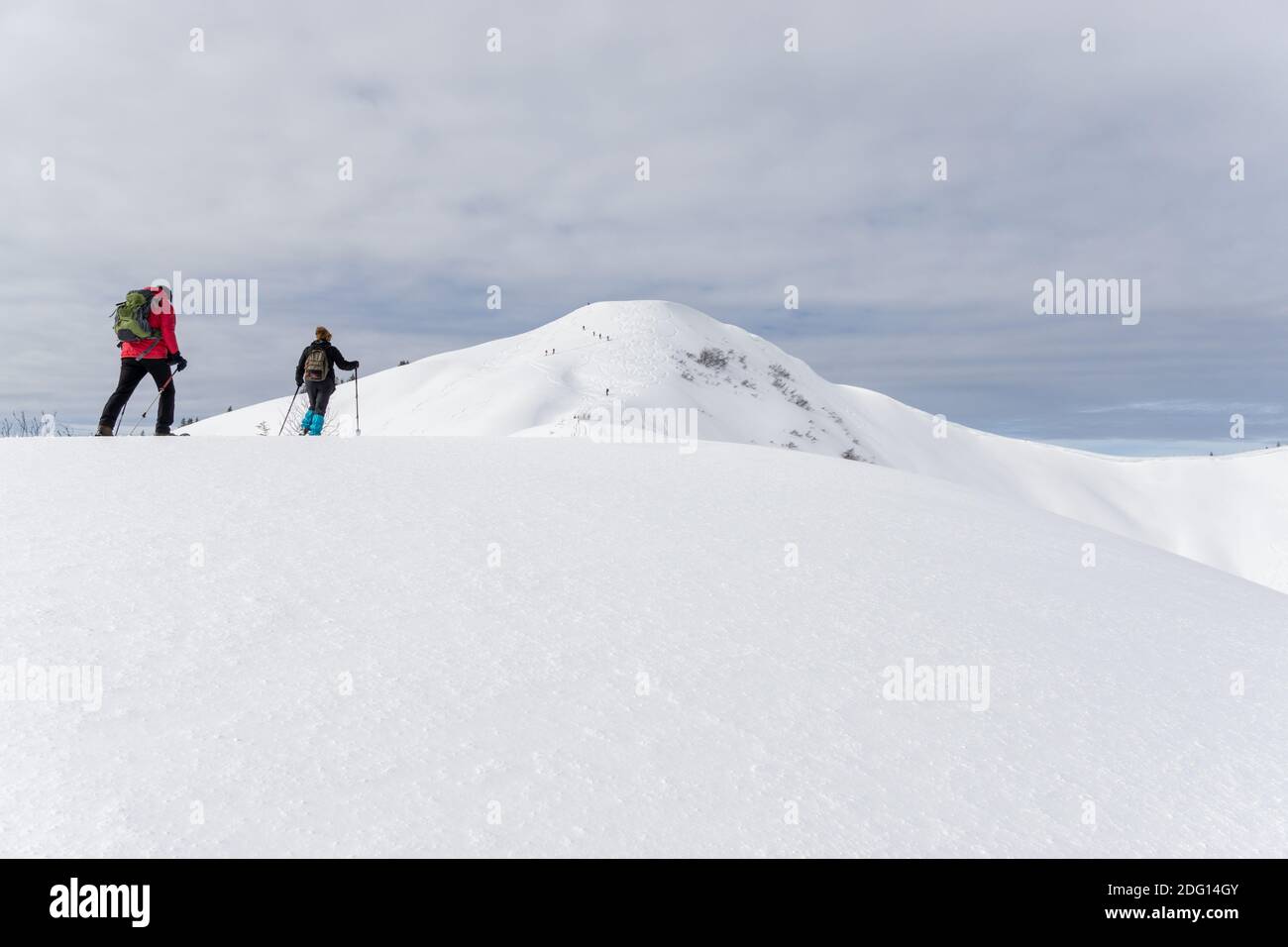 Senior couple is snowshoe hiking in alpine snow winter mountains. Allgau, Bavaria, Germany. Stock Photo